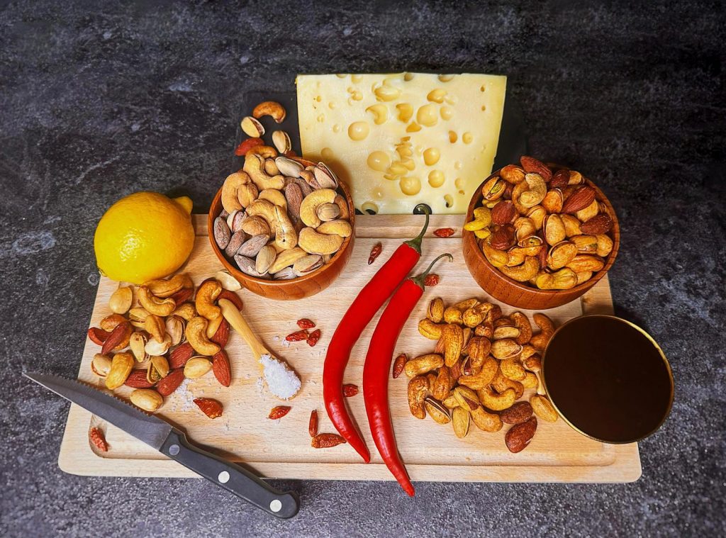 Edle Nussmischung mit gerösteten Cashewkernen, Mandeln und Pistazien, serviert in Holzschalen auf einem natürlichen Holzbrett. Frische Zitronen im Hintergrund sorgen für einen Hauch von Frische – ideal für gesunde Snacks, Party-Highlights oder als Gourmet-Geschenk. Hochwertig, knackig und voller Geschmack. #Nussmischung #GesundeErnährung #SnacksFürUnterwegs #GourmetNüsse